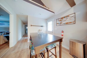 A dining area with a wooden table and chairs, a vase on the table, and a fire extinguisher on the wall. - 'Wishin & Fishin' Walkable Erie Home By the Beach! (Erie)