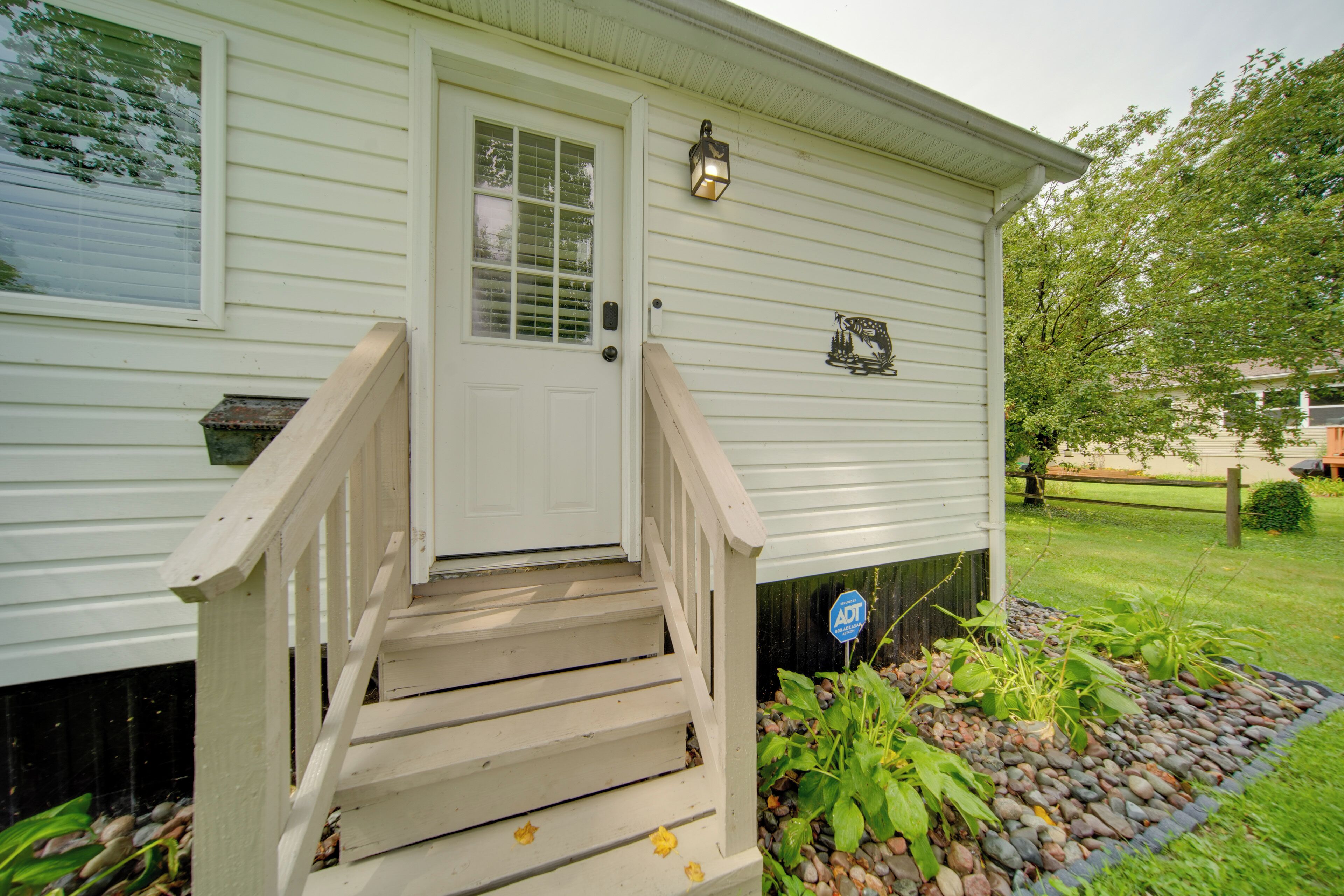 A white single-story house with a front door, a small porch with steps, and a mailbox.