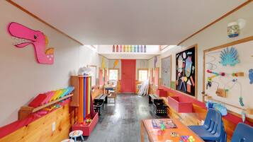 A brightly colored children's playroom with wooden furniture, colorful decorations, and educational materials.