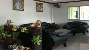 A living room with a black leather sofa, a wooden coffee table, and two framed pictures on the wall. - Wanpen Place (Udon Thani)