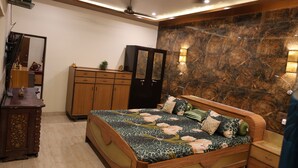 A bedroom with a bed, wooden wardrobe, and a marble wall. - Shreejee The Farm | Huge Farm•Pool•Party•Desi Fun (Sancholi Village)