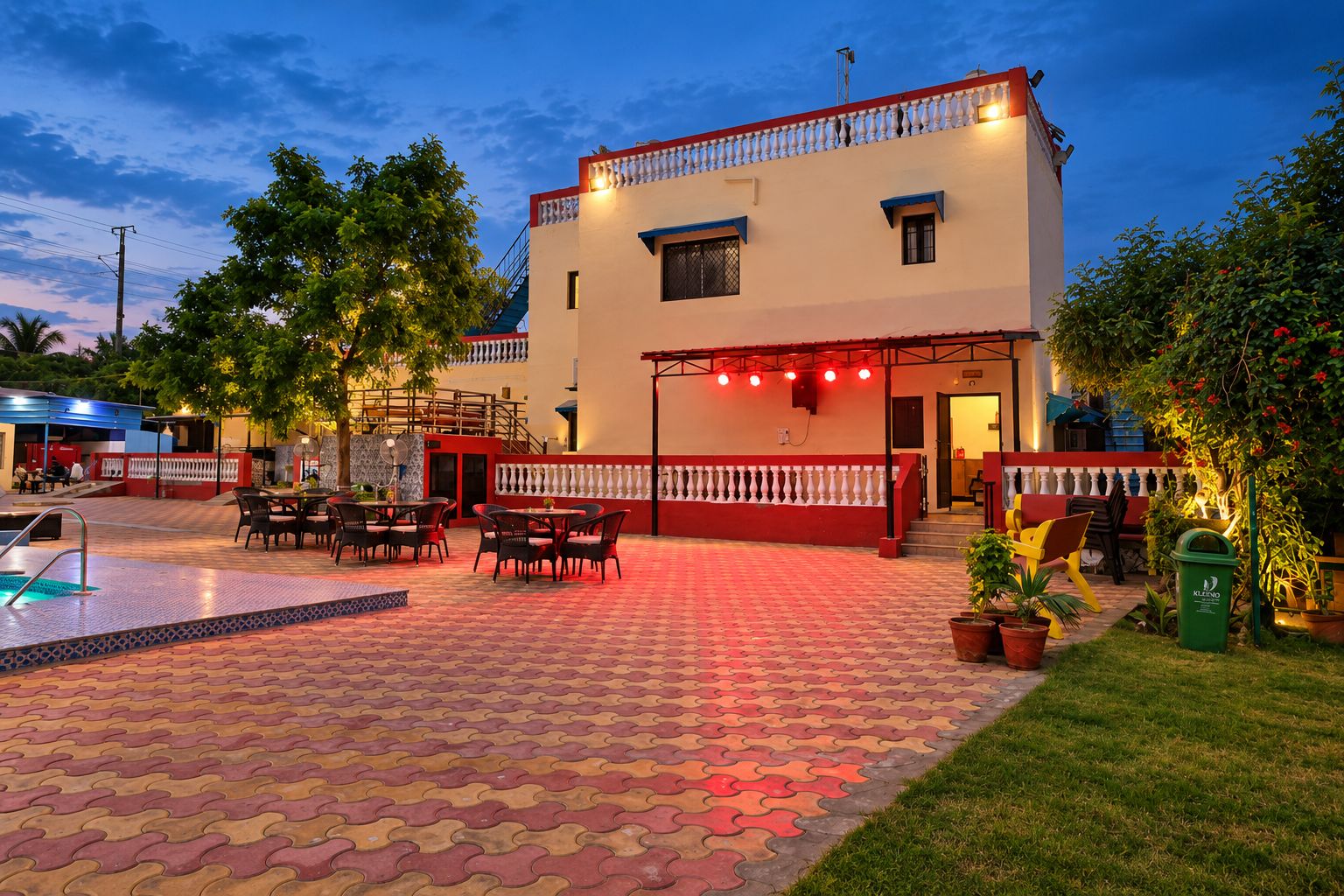 A hotel with a pool, outdoor seating, and a well-lit entrance.