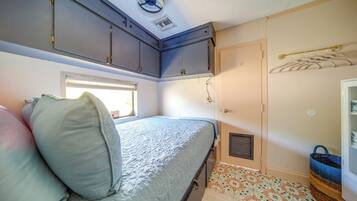 A compact bedroom with a bed, a window, a wardrobe, and a small bathroom area.