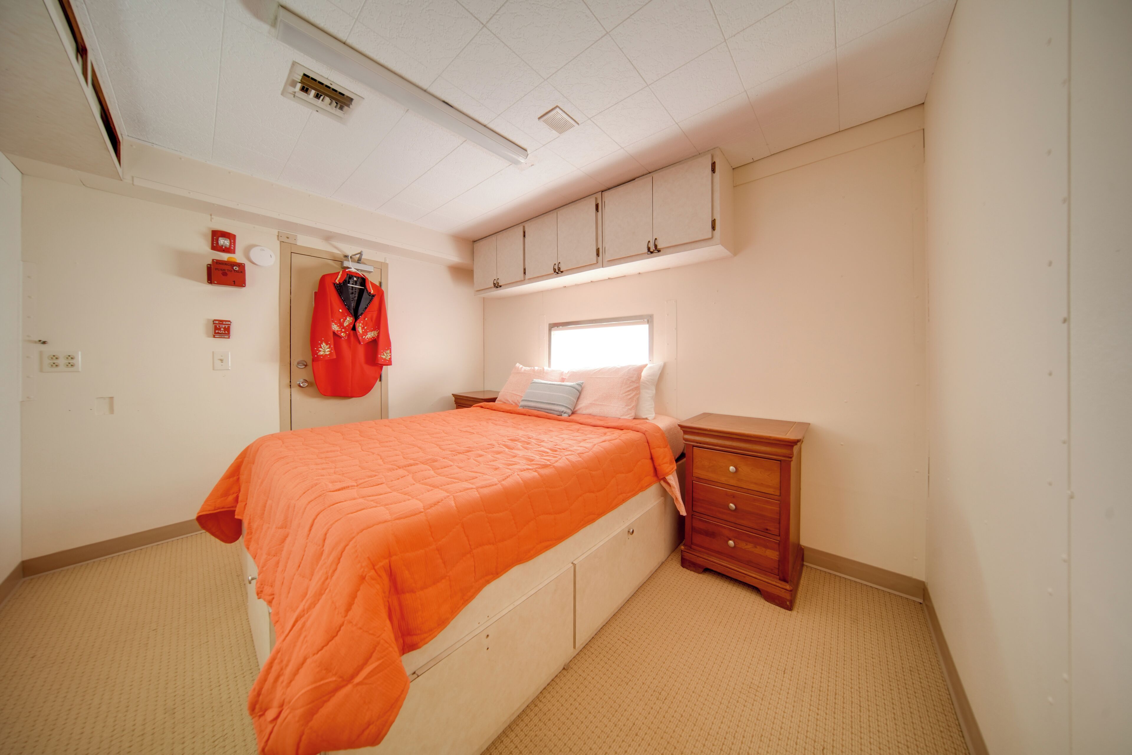 A bedroom with a bed, a dresser, a window, and a closet.