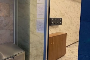 A room with a marble wall, a wooden cabinet, and a door with a paper on it. - Asobo osaka nipponbashi Apartment (Osaka)