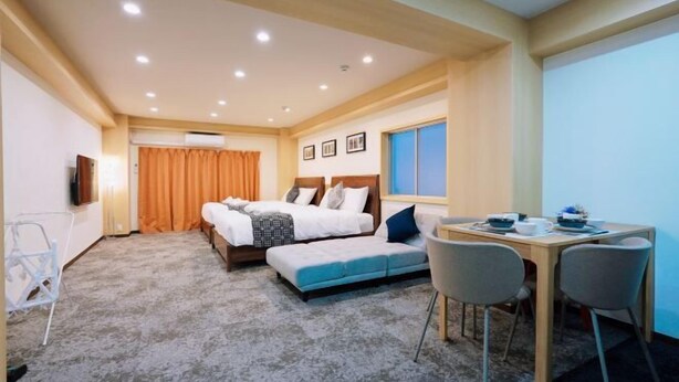 A hotel room with a double bed, a desk with two chairs, a small table, and a television. - Asobo osaka nipponbashi Apartment (Osaka)