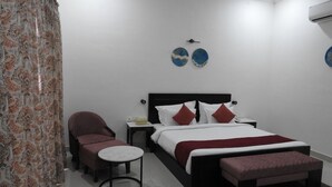 A modern bedroom with a bed, a chair, a small table, and decorative plates on the wall. - Gokul Jawai (Bali)