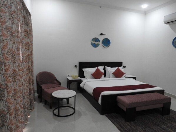 Un dormitorio moderno con cama, una silla, una mesita y platos decorativos en la pared.