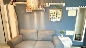 A living room with a grey sofa, a wall-mounted bulletin board, and a small table with a lace tablecloth. - RED PANDA COMMERCE (Seoul)