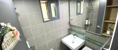 A bathroom with a shower, sink, and toilet.