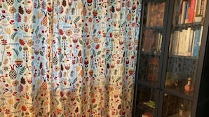 A room with a patterned curtain, a bookshelf, and a cabinet with decorative items. - RED PANDA COMMERCE (Seoul)