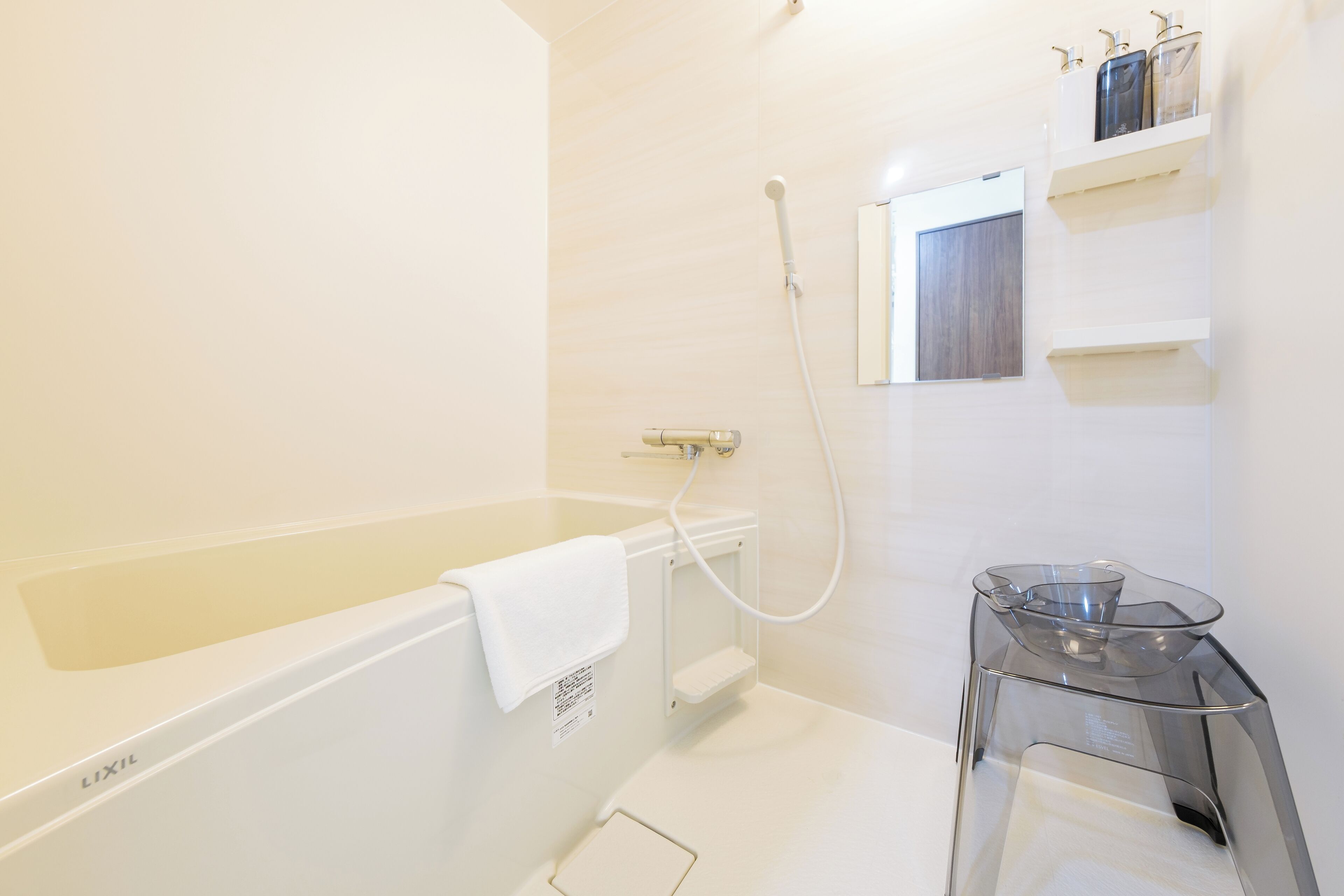 A modern bathroom with a bathtub, a glass shower enclosure, and a small table with toiletries.