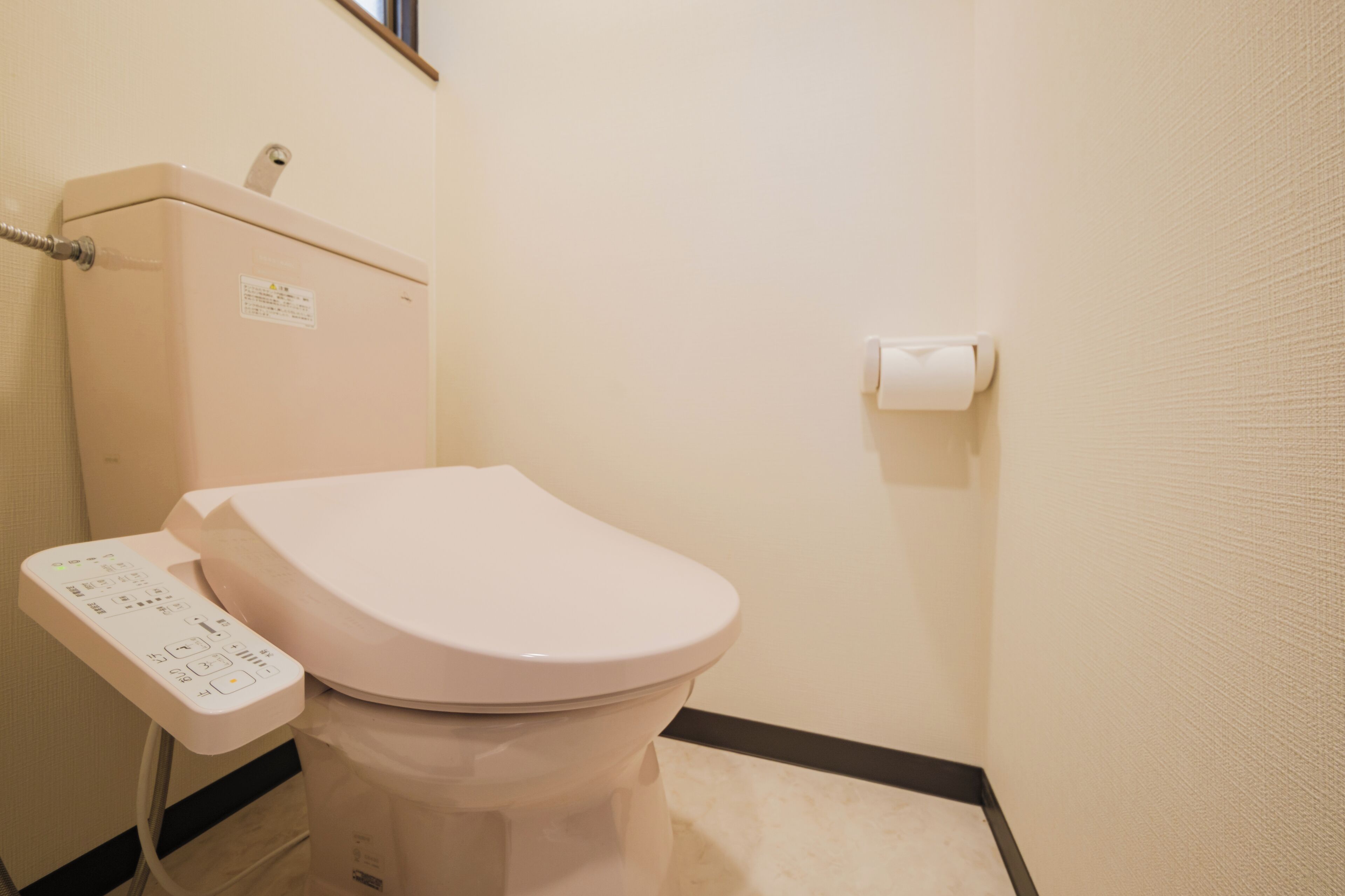 Eine Toilette mit Bedienfeld und Papierhalter an der Wand.
