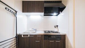 Uma cozinha compacta com armários de madeira escura, uma pia dupla, forno embutido e fogão a gás.