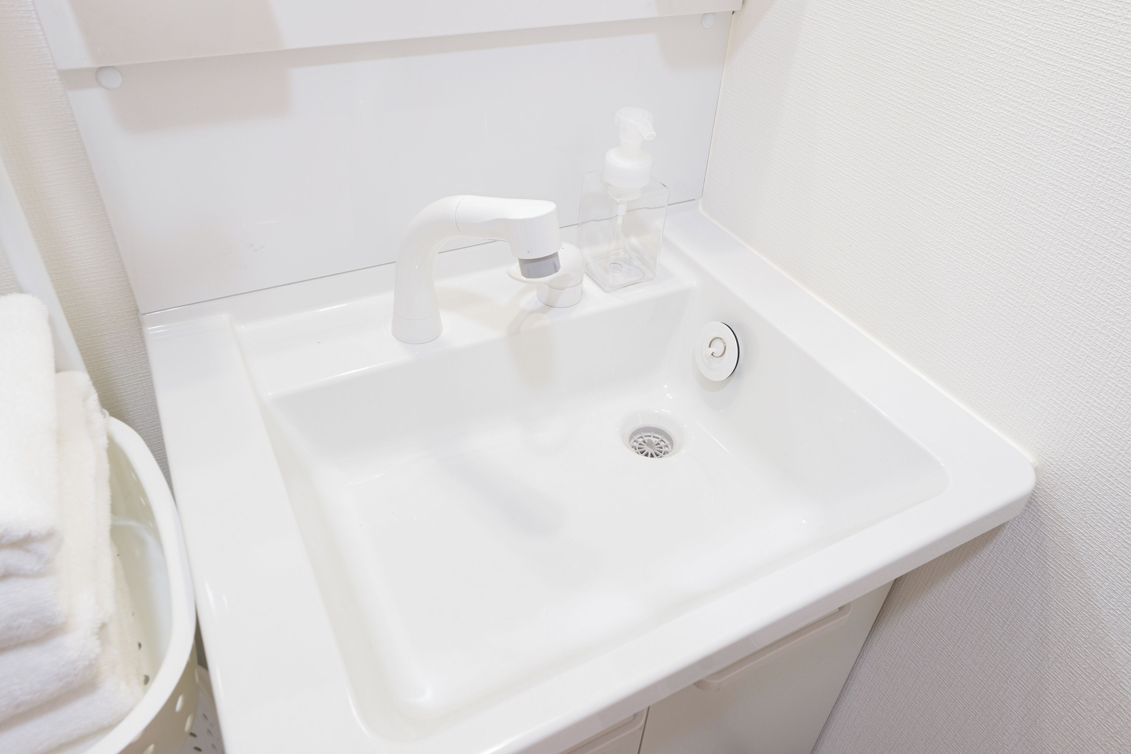 A white bathroom sink with a modern faucet, a soap dispenser, and a small trash bin.
