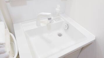 A white bathroom sink with a modern faucet, a soap dispenser, and a small trash bin.