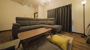 Uma sala de estar moderna com um sofá seccional, uma mesa de centro de madeira e um abajur de chão.
