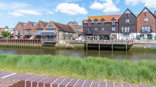 A canal with houses on one side and a church in the background.