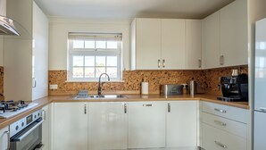 A modern kitchen with white cabinets, a granite countertop, a built-in oven, a coffee maker, and a microwave.