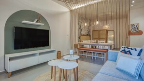 En moderne stue med et fladskærms-tv, en sofa, et spisebord og et lille sofabord.