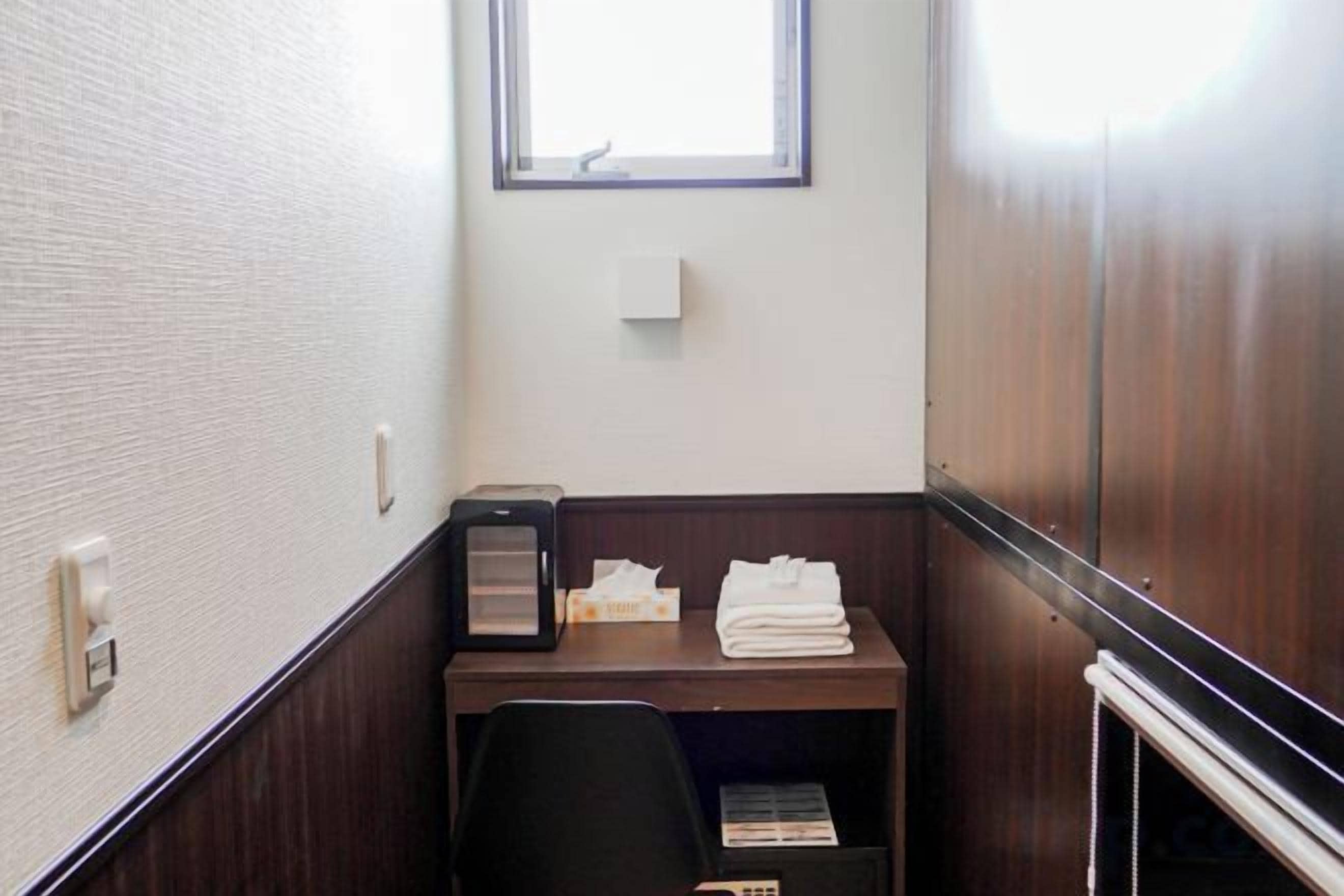 Un pequeño espacio de oficina cerrado con un escritorio, una silla y un ventanal.