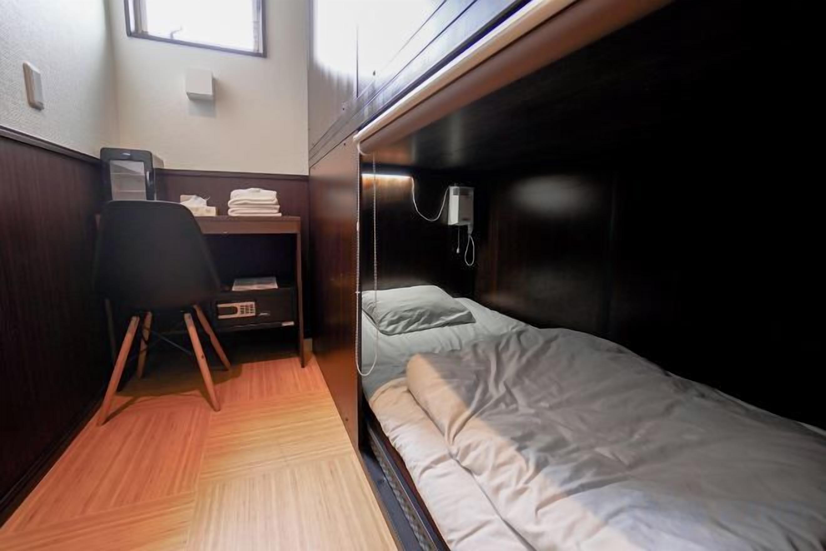 A compact room with a bunk bed, a desk with a chair, and a small window.