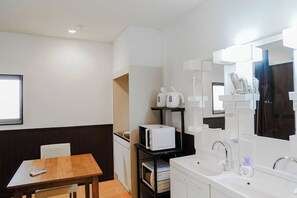A modern hotel room with a wooden dining table, a white sink, and a large mirror. - SAMURAI STAY Senzoku Pond【MALE ONLY】 (Tokyo)