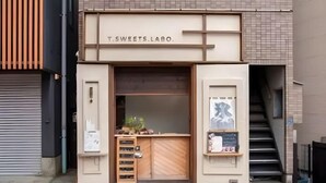 Une devanture de magasin avec une façade en bois, une enseigne indiquant « T.SWEETS LAO » et un petit espace d’exposition où sont présentés divers articles.