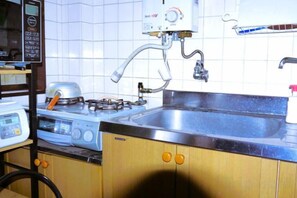 A kitchen with a gas stove, a sink, and a microwave. - Tokyo Yoshimi home stay (Tokyo)