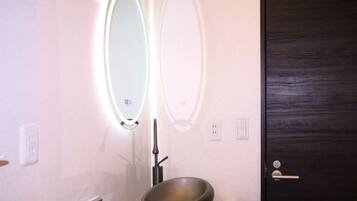 A bathroom with a mirror, a bowl sink, and a dark wooden door.
