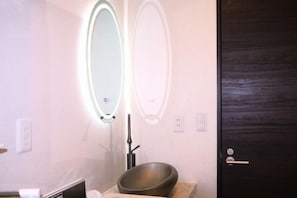 A bathroom with a mirror, a bowl sink, and a dark wooden door. - Tokyo Yoshimi home stay (Tokyo)