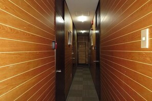 A hallway with wooden paneling and a carpeted floor, leading to a door at the end. - Tokyo Yoshimi home stay (Tokyo)