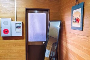 A wooden-paneled room with a door, a security intercom, and a framed picture on the wall.