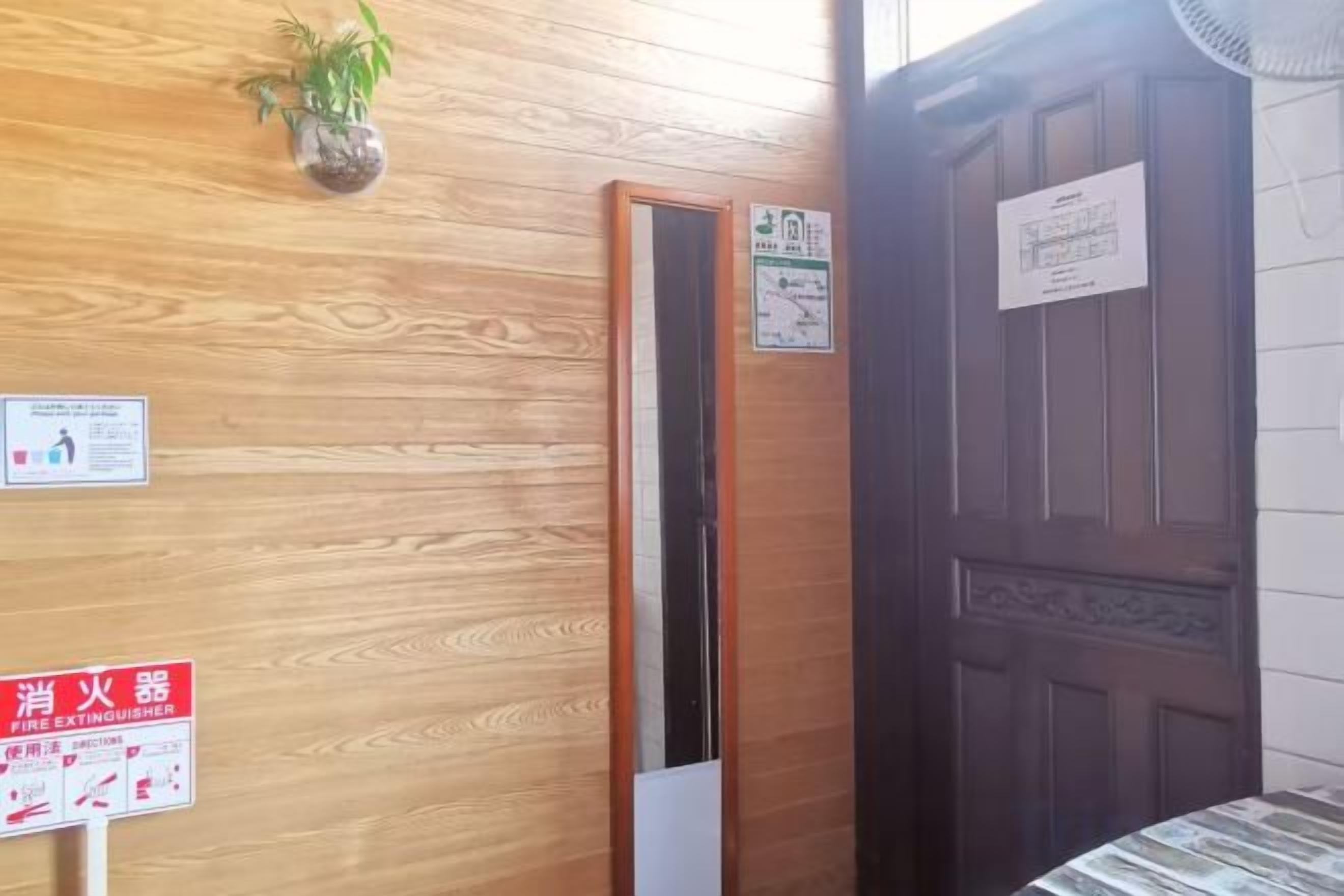 A wooden wall with a door, a sign, and a fan.