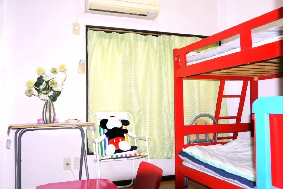 A bunk bed with a ladder, a desk with a chair, and a window with curtains.