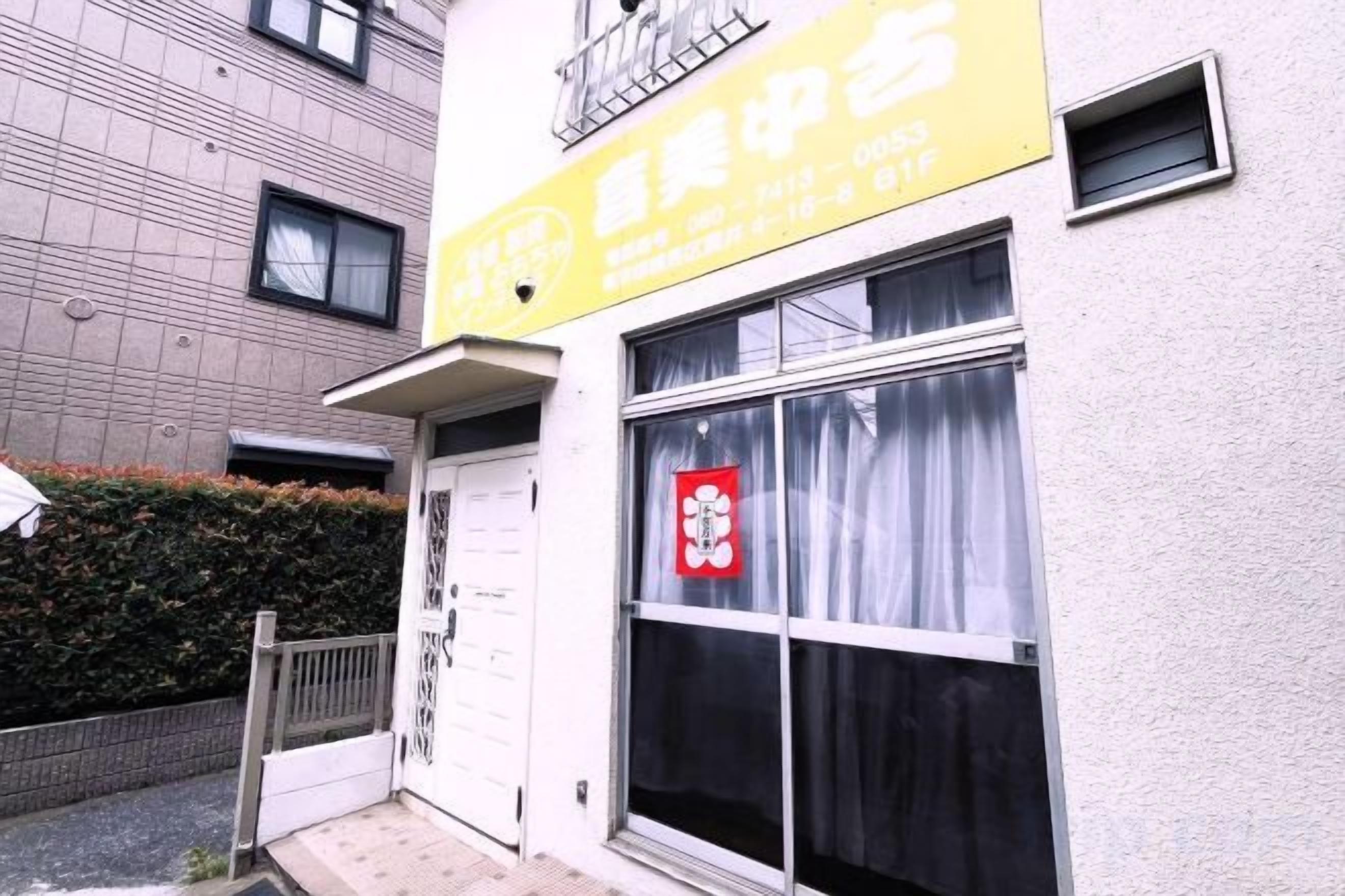 A building with a yellow sign, a white door, and a window with curtains.
