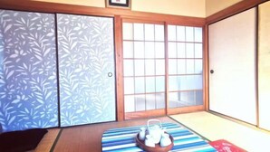 A traditional Japanese room with tatami flooring, shoji screens, and a tea set on a low table. - Tokyo Yoshimi home stay (Tokyo)