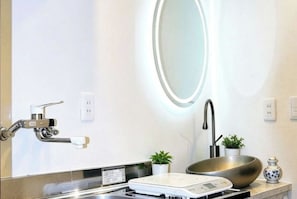 A modern bathroom with a large mirror, a sink with a vessel basin, a scale, and a small potted plant. - Tokyo Yoshimi home stay (Tokyo)