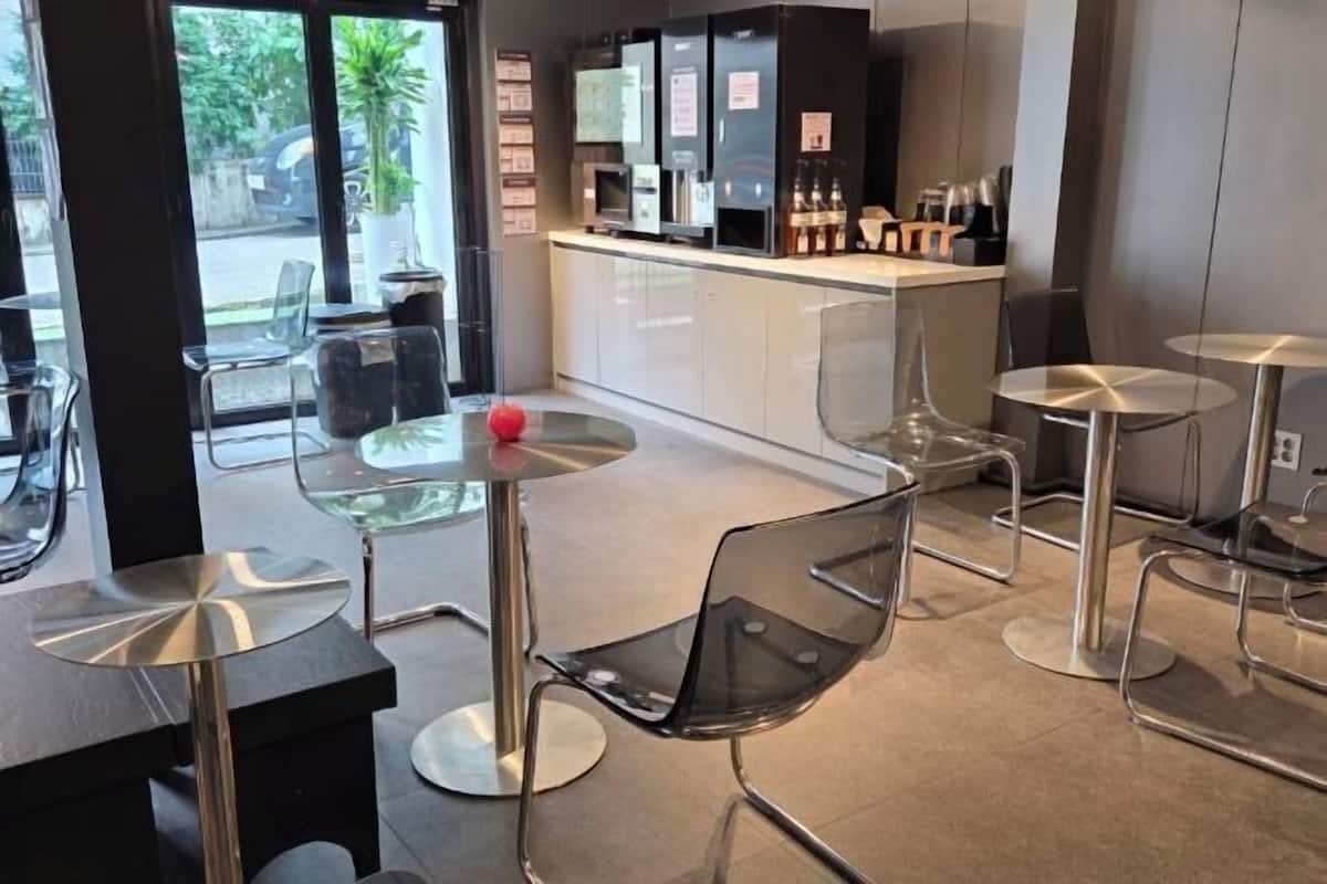 A modern cafe with glass tables and chairs, a counter with beverages, and a view of the street.