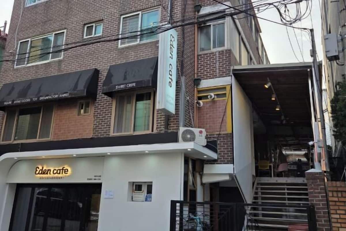 A building with a sign for Eden Cafe, a brick facade, and a staircase leading to an upper level.