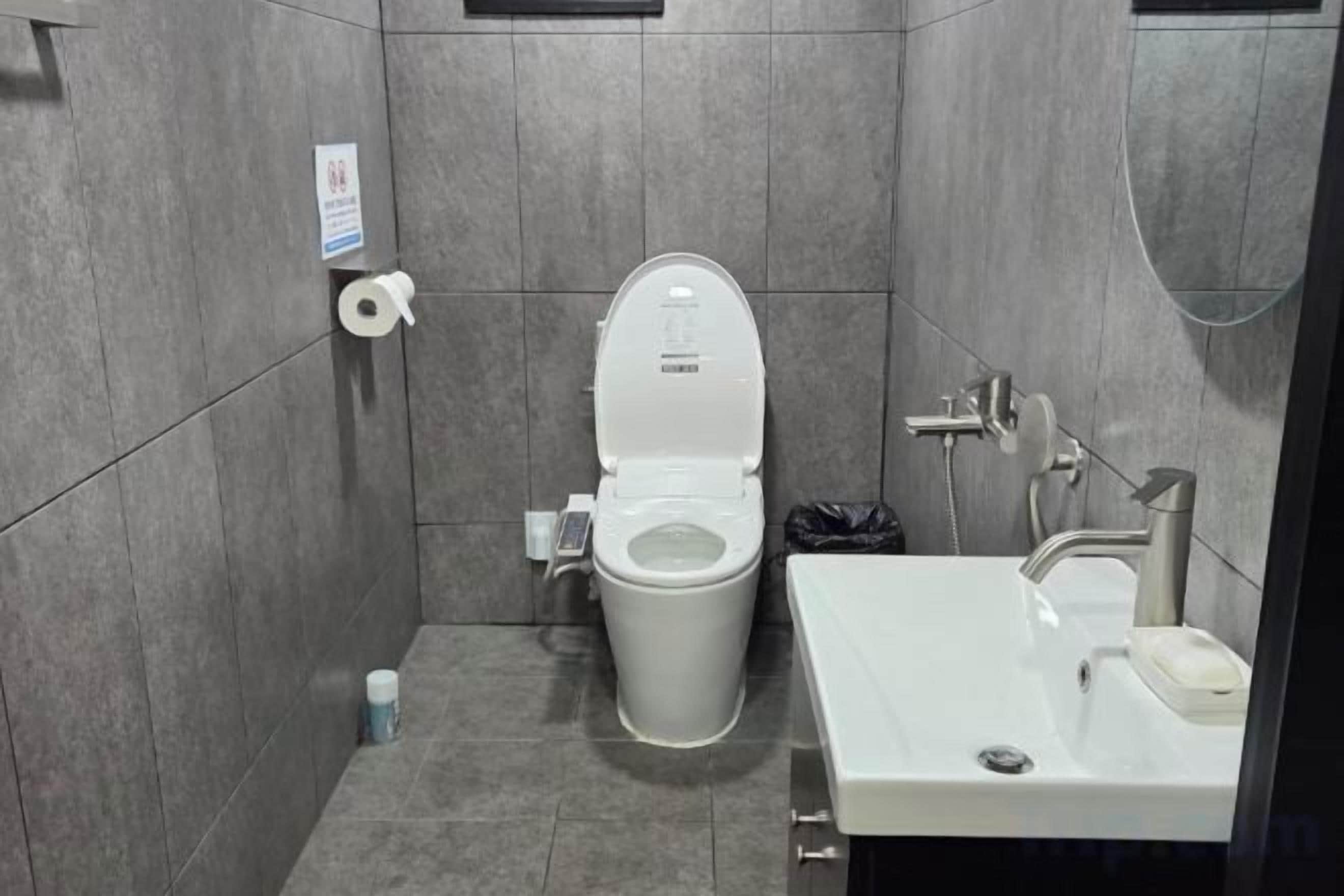 Casa de banho moderna com sanita, lavatório e chuveiro.