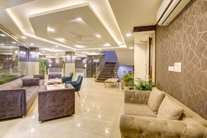 A spacious lobby with a modern design, featuring a seating area with sofas and chairs, a staircase, and a glass wall providing a view of the outdoors. - The Prithvi Palace Delhi (New Delhi)