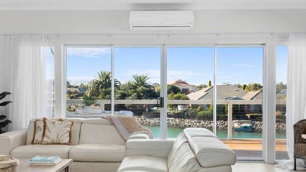 Una sala de estar moderna con un ventanal grande que da a una piscina y vistas a una zona residencial.