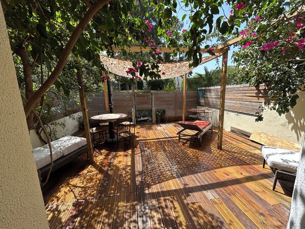 Eine Holzterrasse mit Pergola, Sitzgelegenheit und einem Tisch.