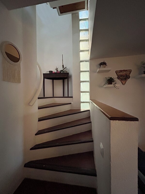 Una escalera con barandilla de madera y una pequeña mesa con plantas en la parte superior.