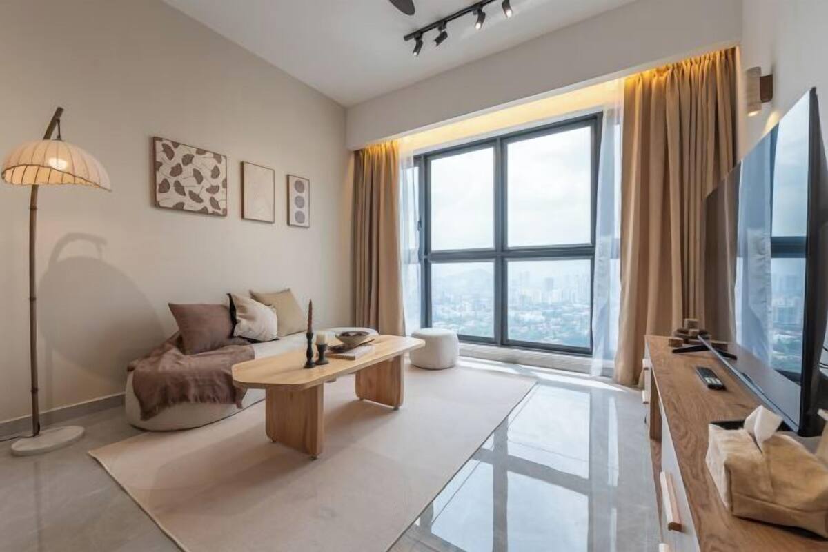 A modern living room with a large window, a sofa, a coffee table, and a TV.