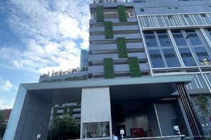 Un bâtiment moderne doté d’un toit plat, de grandes fenêtres et d’un jardin vertical verdoyant sur la façade.