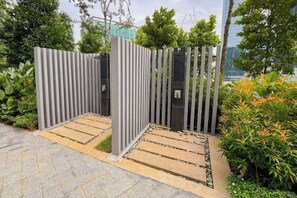 A gated entrance with vertical slats, a paved pathway, and surrounding greenery. - Agile Bukit Bintang TRX Pavilion by FaceHome (Kuala Lumpur)