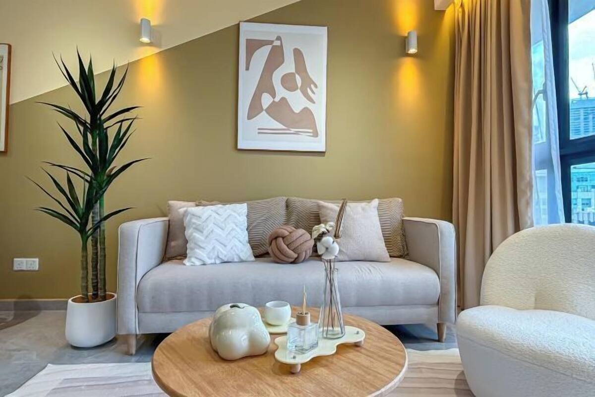A modern living room with a sofa, a coffee table, a potted plant, and a wall-mounted artwork.