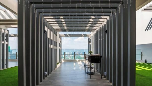Un pasillo con vistas a la ciudad, que presenta un diseño arquitectónico moderno con columnas verticales y suelo de baldosas.
